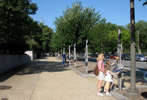 The Voyage Scale Model Solar System in Washington, DC. This photo shows the author's family at the model Sun, which is the gold-colored sphere. Looking into the distance you can see the pedestals for the inner planets. The National Air and Space Museum is on the left.